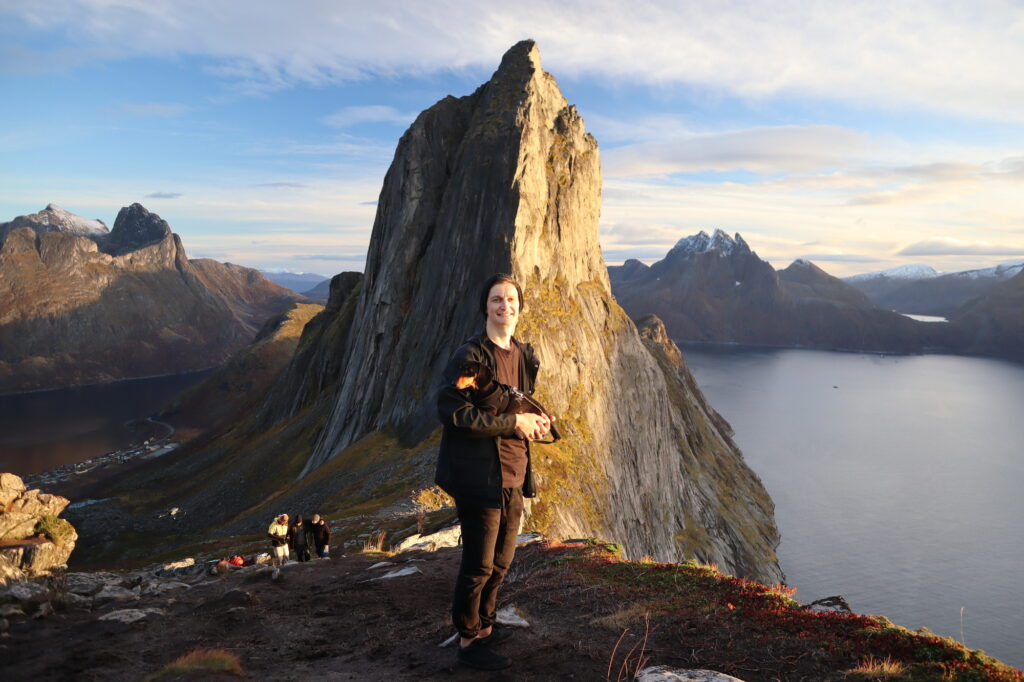 man holding dog standing in front of segla mountain in norway