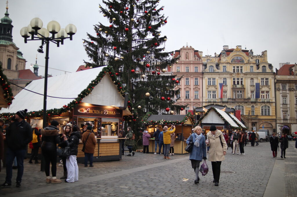 people walk by christmas markets in prague