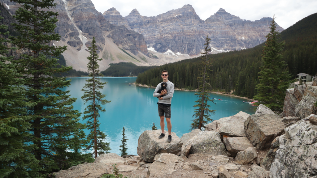 man holding small dog at Moraine Lake in Canada